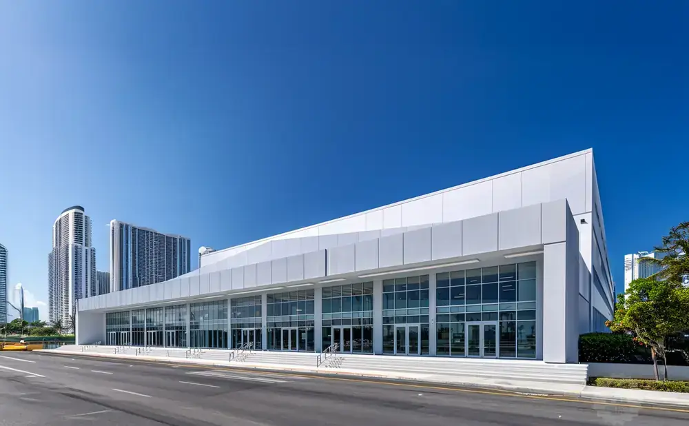 Modern convention center with glass facade and white angled roof against a clear blue sky.