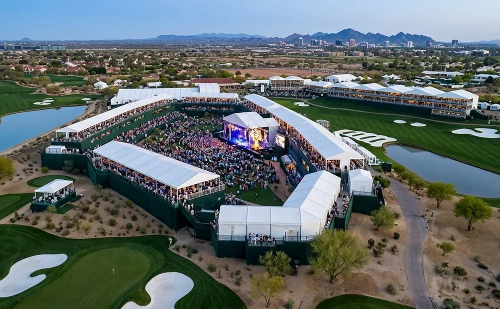 Aerial view of a golf tournament with a large concert stage and spectator seating area.