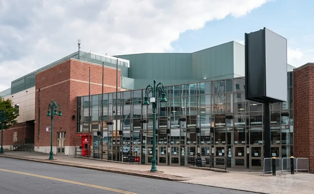 A modern brick and glass building with a large blank billboard in front.