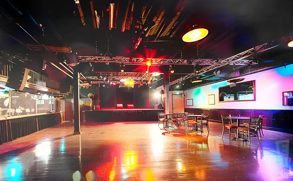 A nightclub stage, tables, and bar area lit with colorful stage lights.
