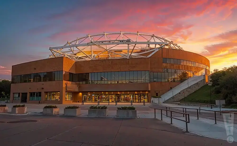 A large, modern building with a domed roof, at sunset.