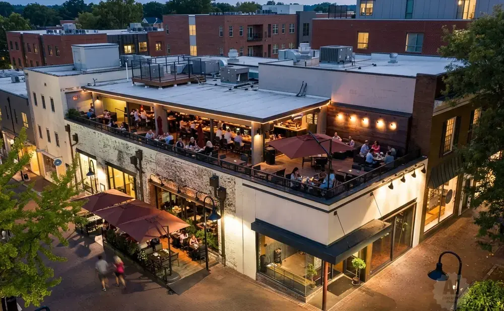 Rooftop restaurant with patrons dining and socializing at dusk.