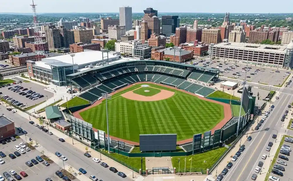 Aerial view of a baseball stadium surrounded by a city skyline and parking lots.