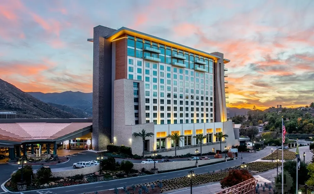 A hotel at sunset with mountains and a colorful sky.