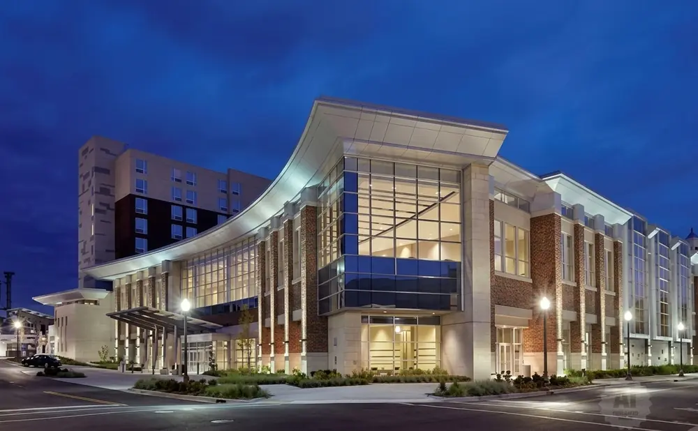 Modern building at dusk with curved facade, large windows, and brick accents.