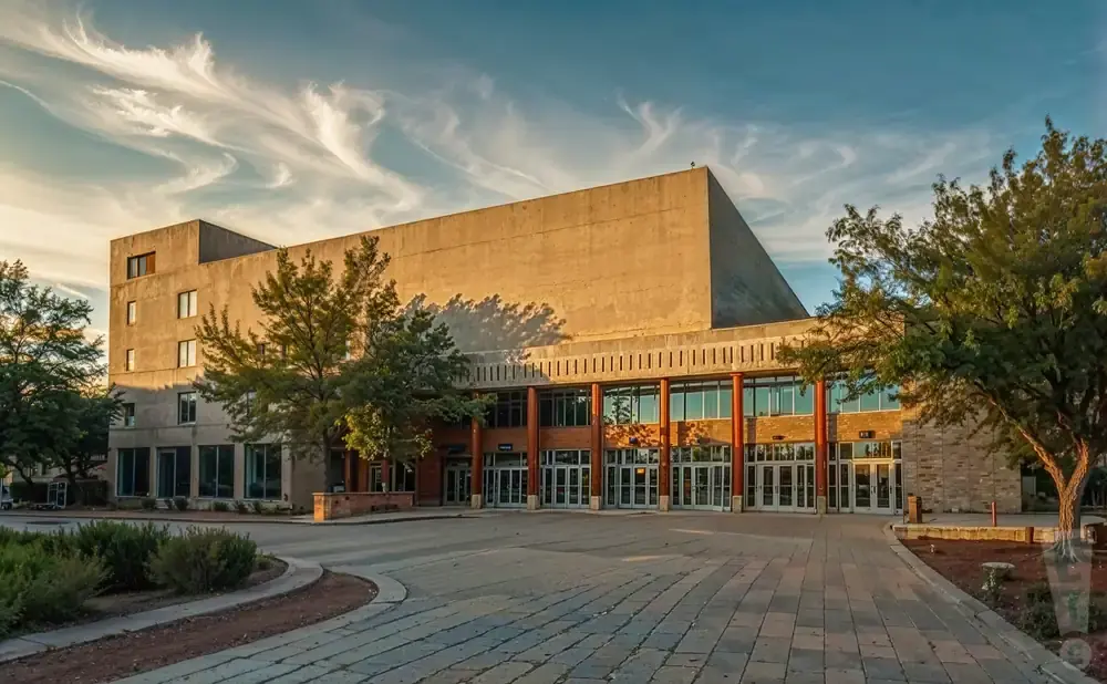 A large brutalist building with a wide paved walkway in front, under a dramatic sky.