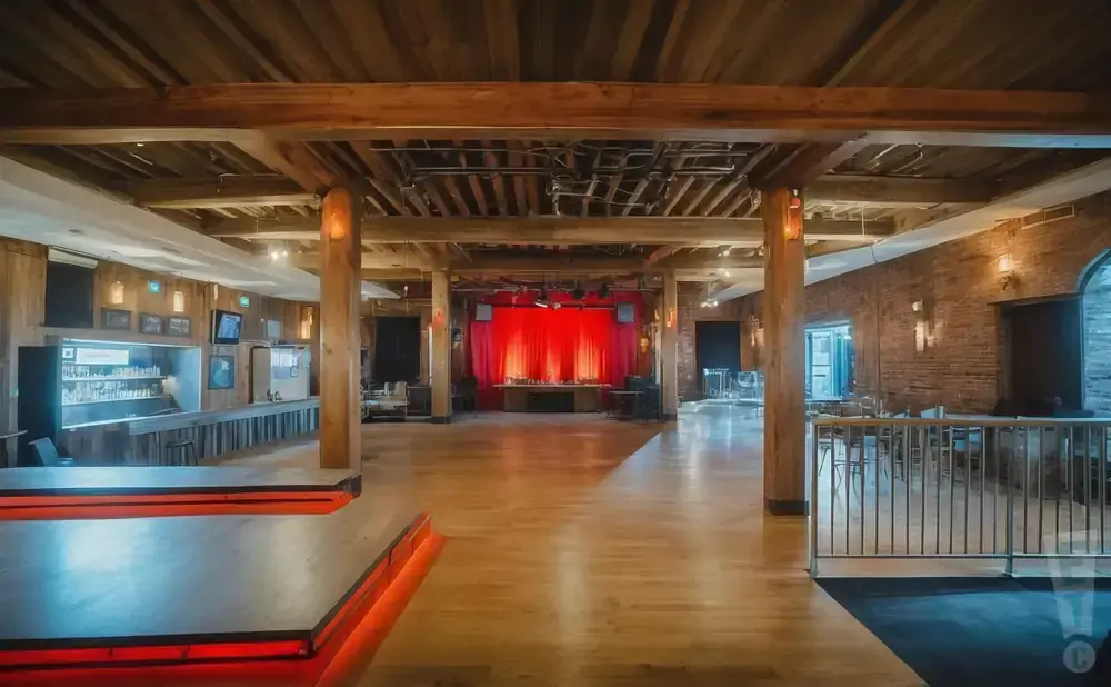 Spacious wooden room with a stage, bar, and seating area.