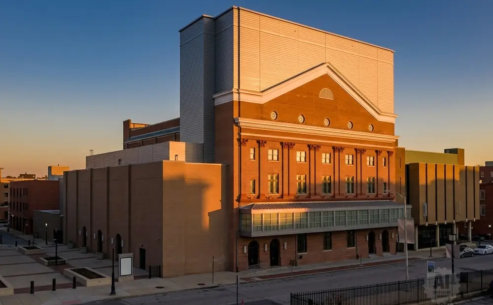 A large brick building with a modern addition and a clear blue sky at sunset.