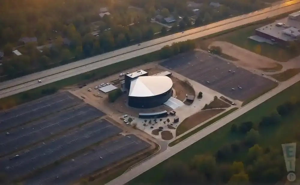 Aerial view of a modern church with a large, curved roof and extensive parking lots.