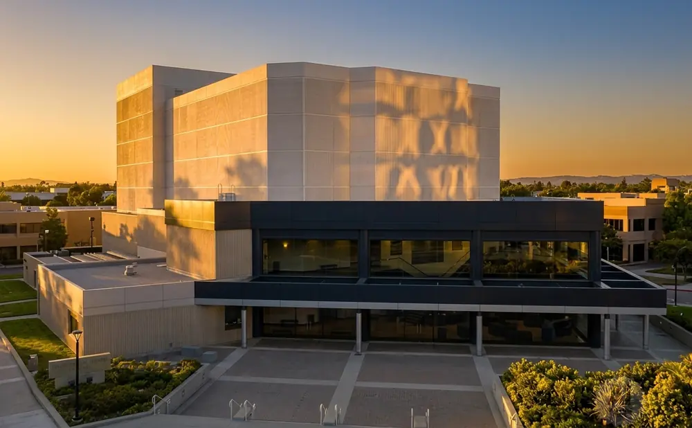 Modern building with large windows and textured walls bathed in golden sunset light.
