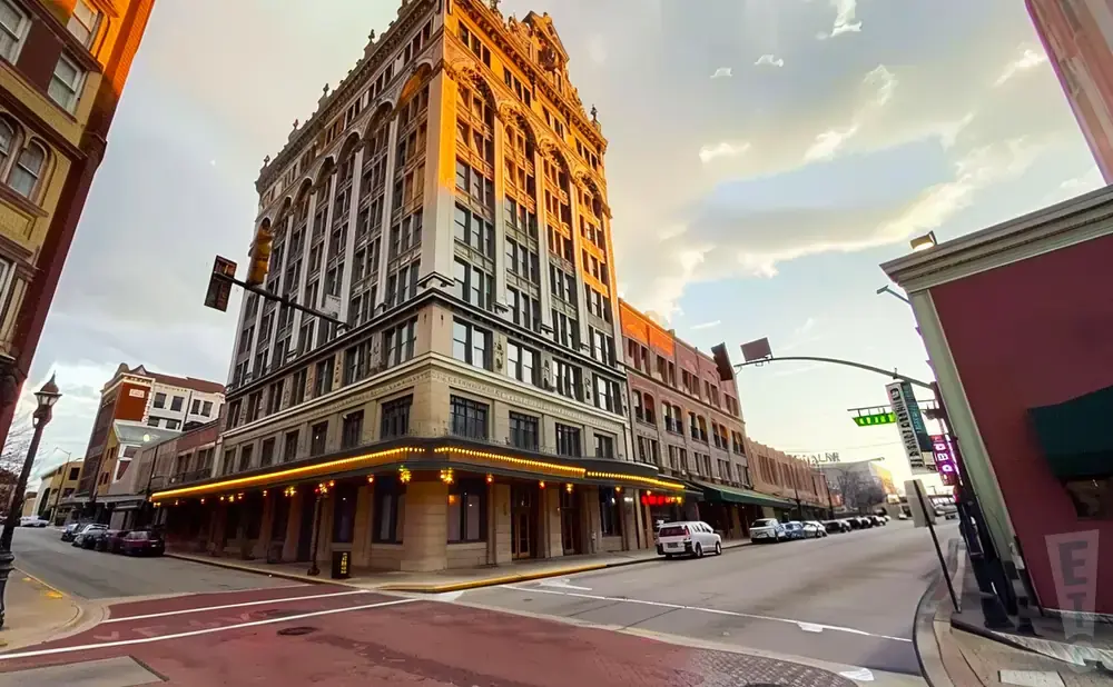 A street view of a grand, historic building with ornate architecture bathed in golden sunset light.