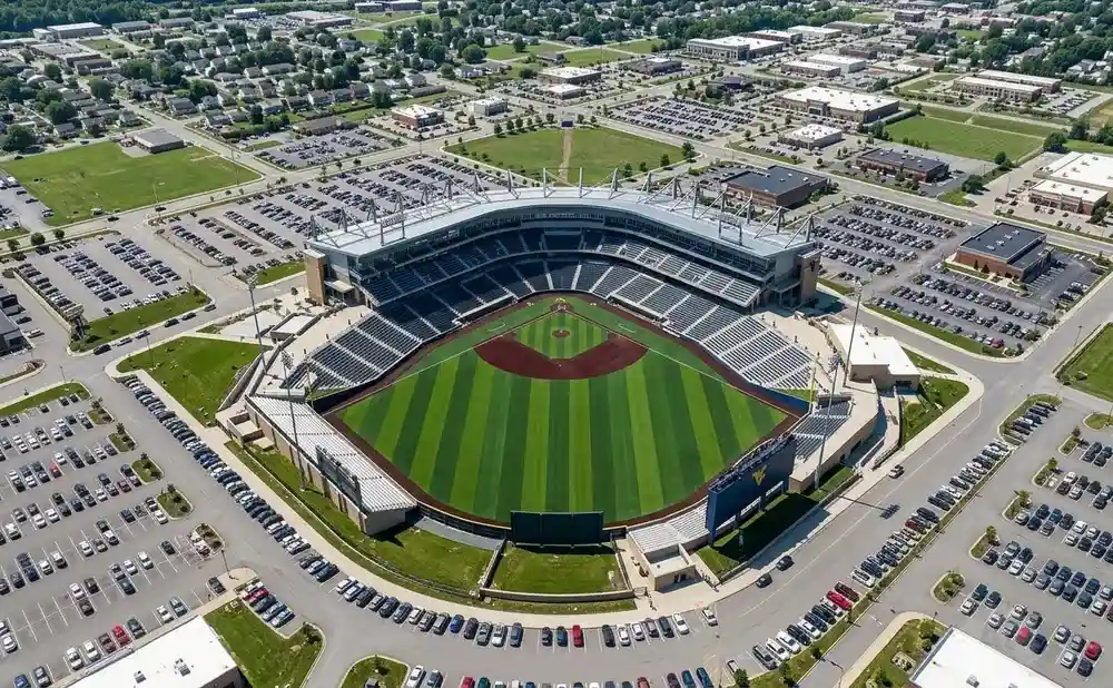 Aerial view of a baseball stadium with a green field and surrounding parking lots, buildings, and residential areas.