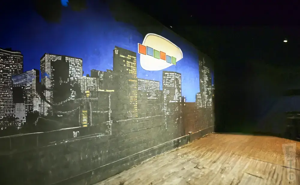 A mural of a city skyline at night with a white oval shape containing colorful squares floating above.