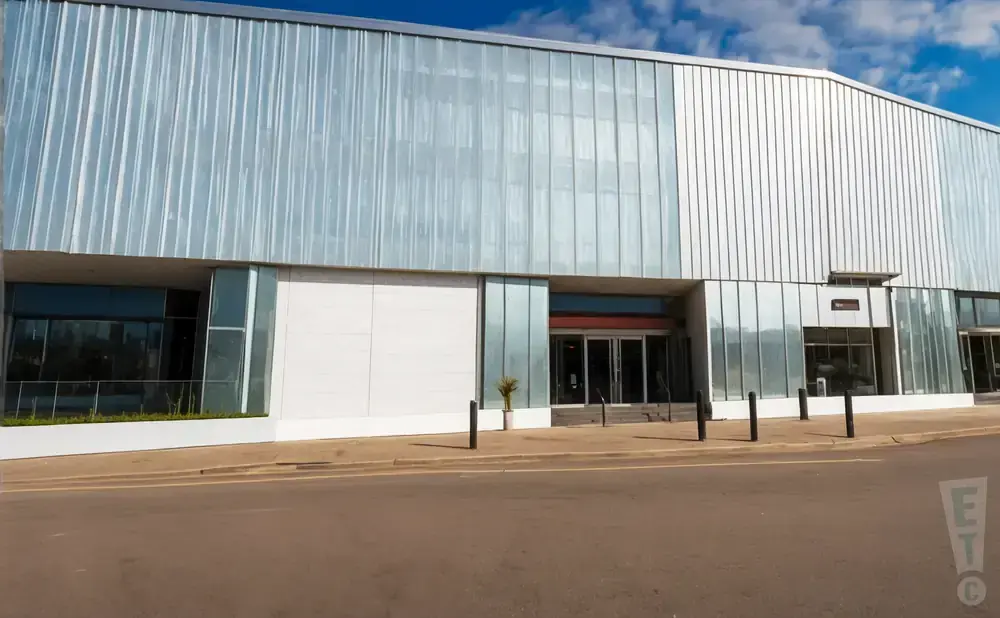 A modern building with a corrugated metal facade and large glass windows.