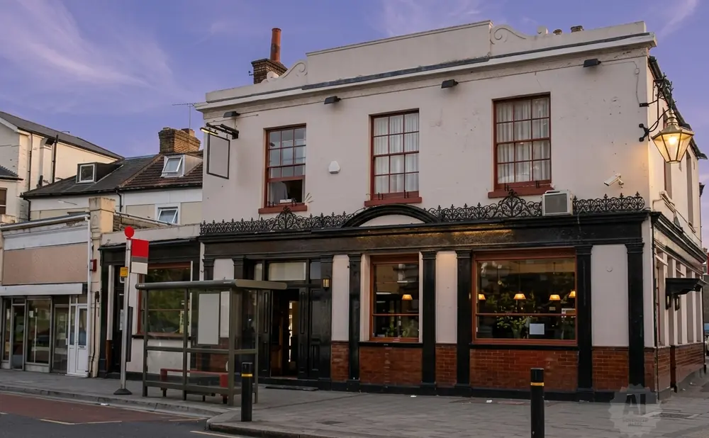 A pale building with a prominent lantern light stands on a street with a bus stop.