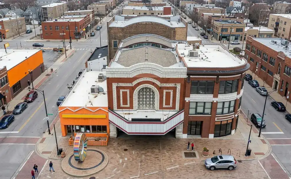 Aerial view of a city street with a historic theater, orange building, and cars.