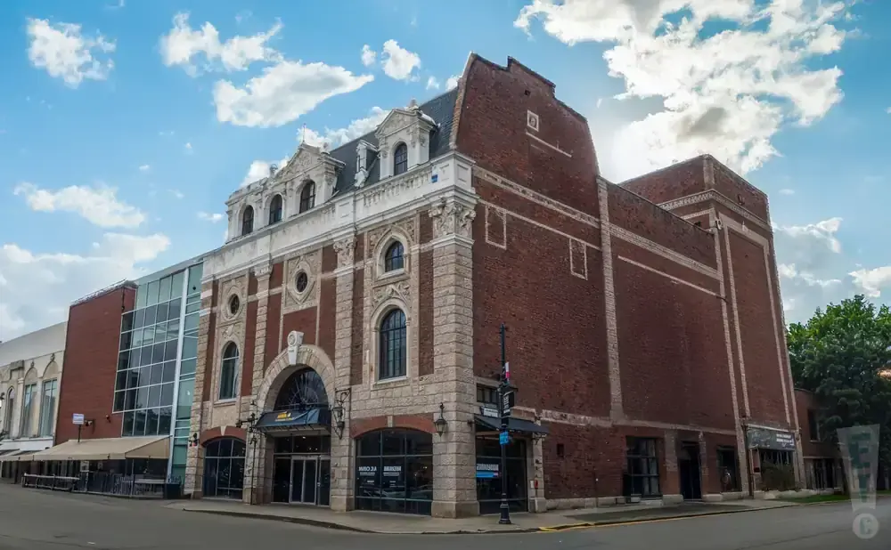 Building with ornate stone facade and brick addition under a cloudy sky.