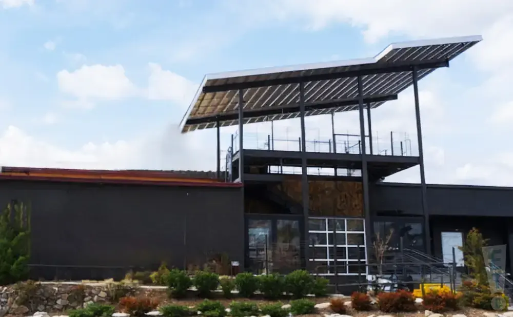 Modern building with dark exterior, multi-level balconies, and a solar panel-covered roof.