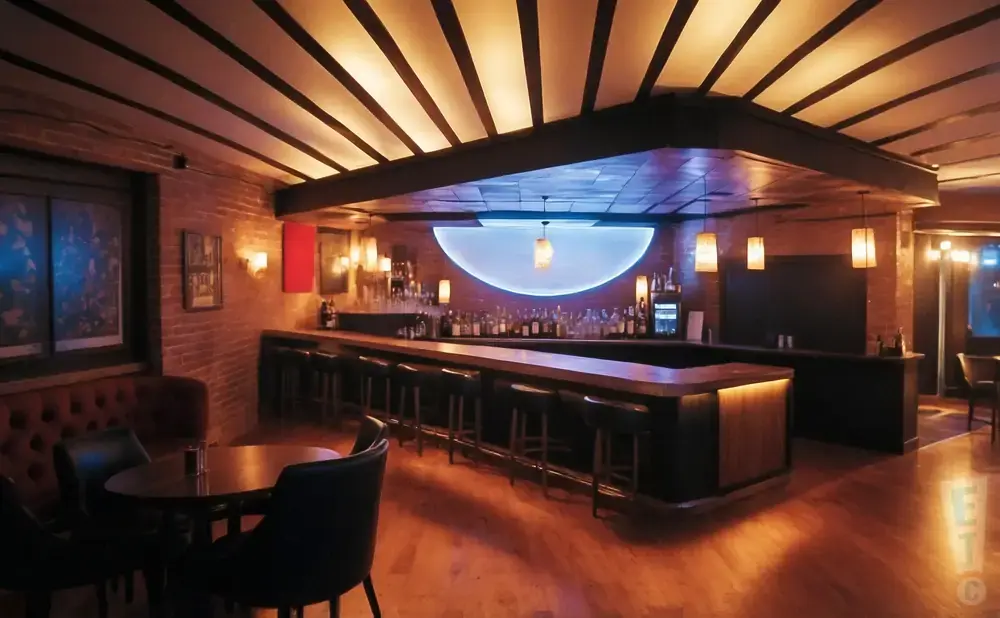 Dimly lit bar with a long counter, stools, and bottles. A semi-circular blue light illuminates the back wall.