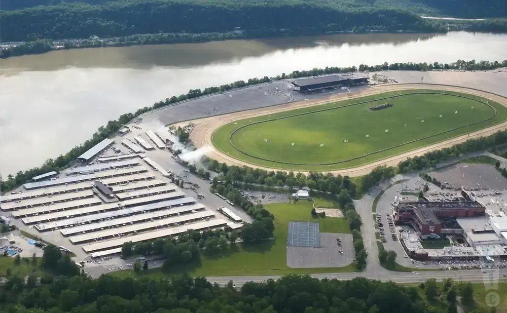 Aerial view of a horse racing track with grandstands, stables, and a casino.