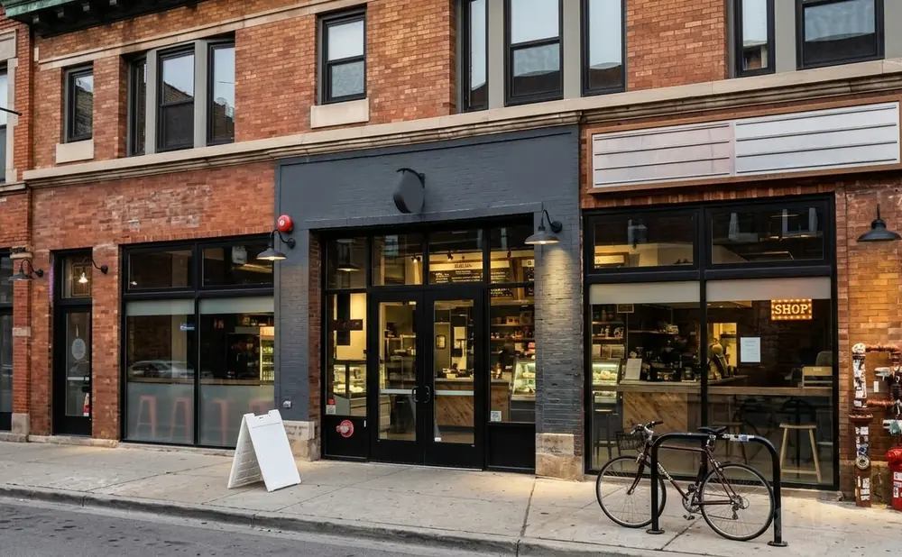A brick building with storefronts, including a cafe and a shop with a 