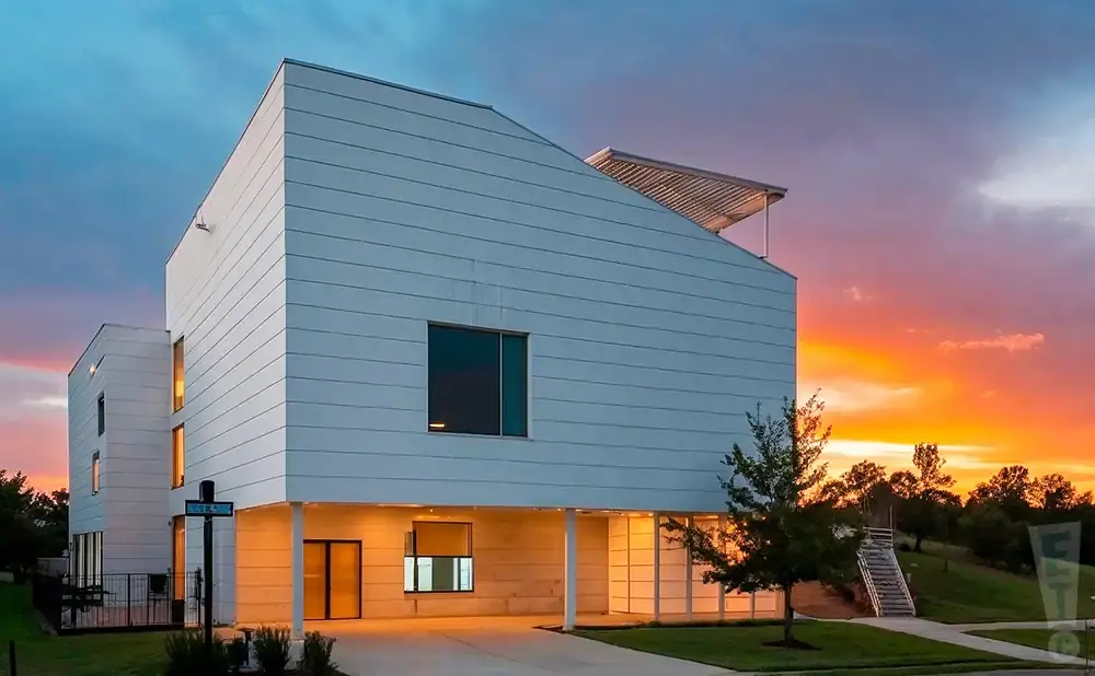 Modern white house with angular roof at sunset.