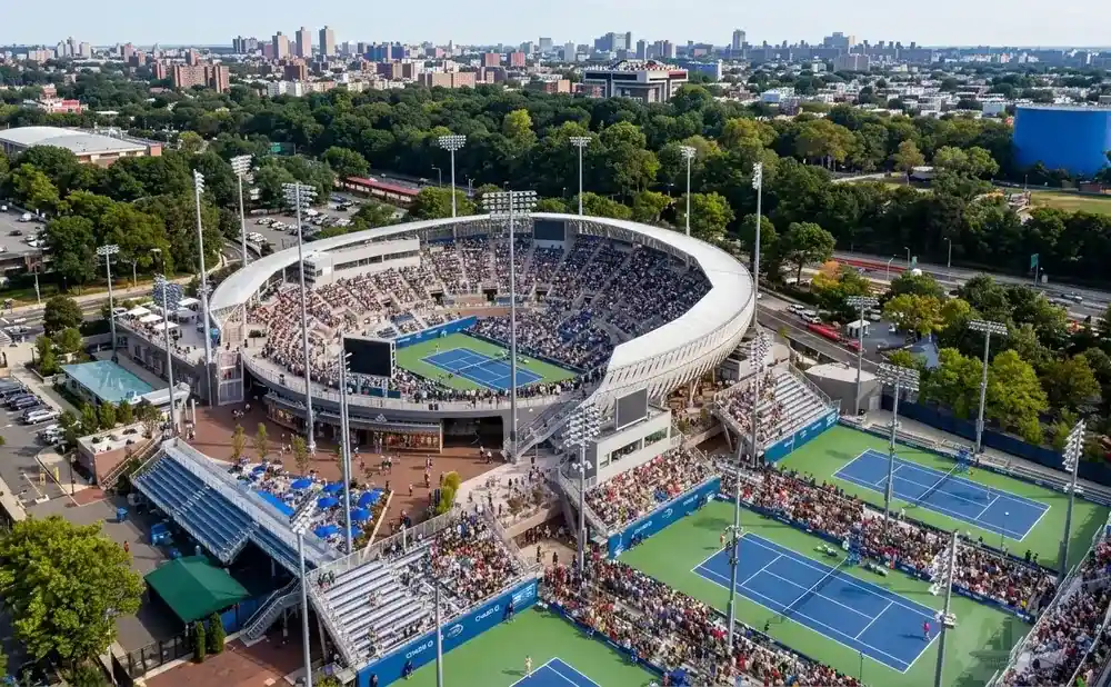 Aerial view of a large tennis stadium and surrounding courts filled with spectators.