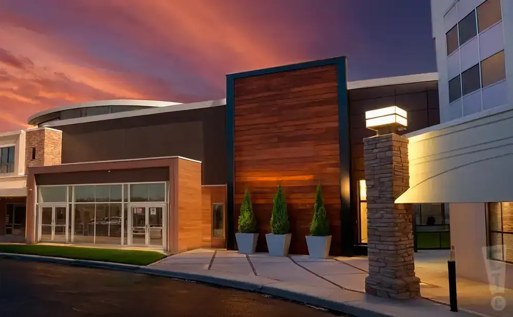 Modern building at dusk with warm wood accents, stone pillar, and a vibrant sunset sky.