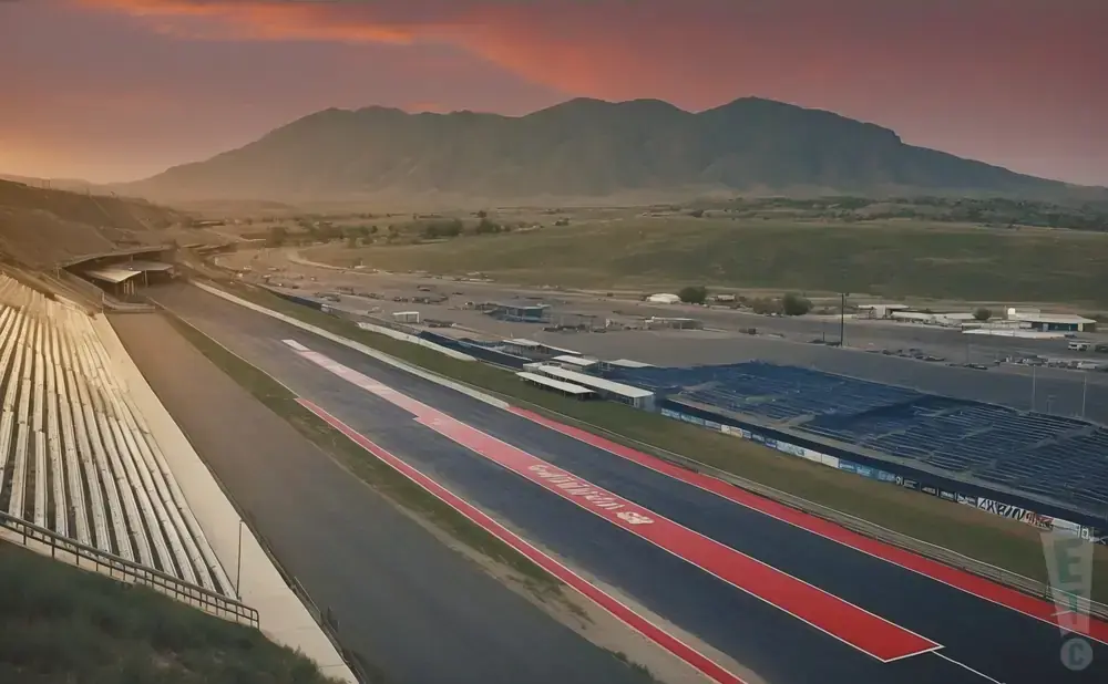 Race track with grandstands and mountains at sunset.