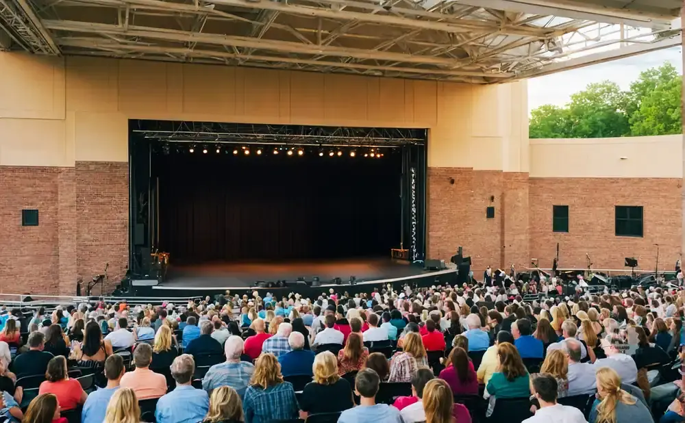 An outdoor amphitheater crowd faces a stage under a large roof.