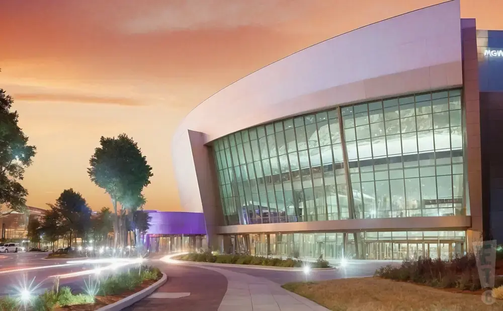 Modern convention center with a curved glass facade and glowing purple accents at sunset.