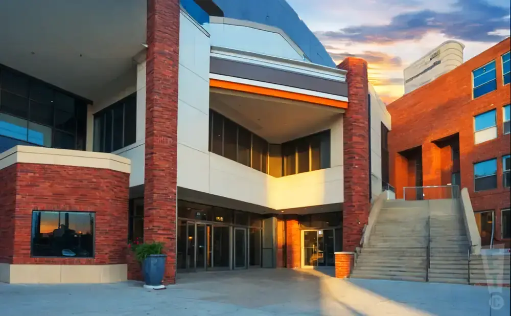 Modern brick and white building with glass windows and a wide staircase leading up to an entrance.