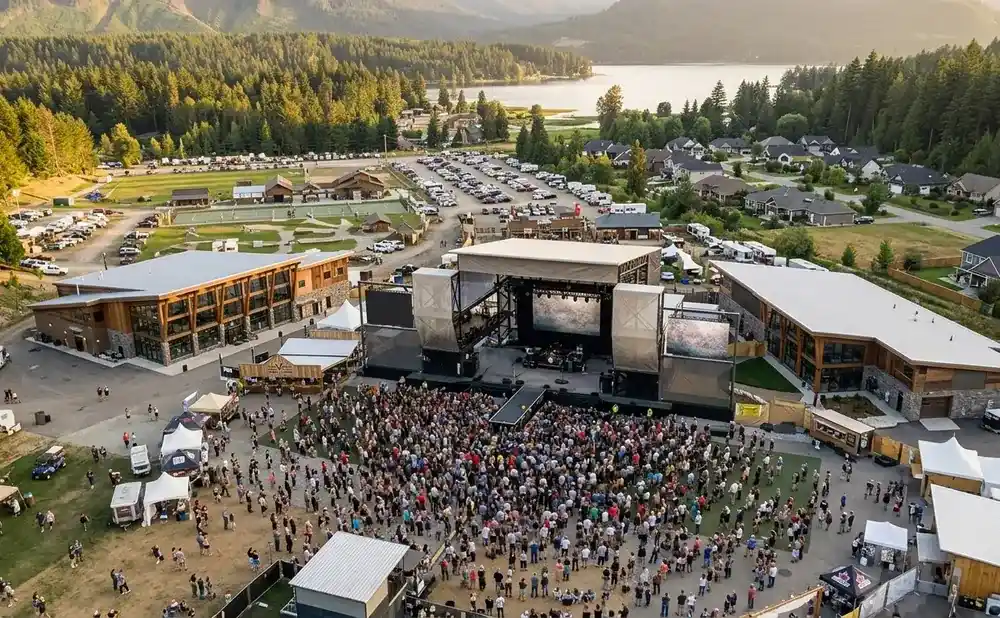 Aerial view of an outdoor concert with a large crowd gathered in front of a stage.
