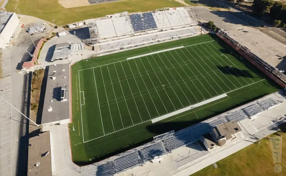 Aerial view of a football stadium with green turf and bleachers.