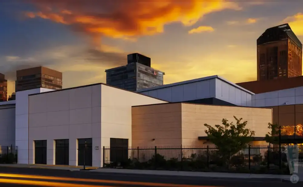 Modern buildings with a vibrant sunset sky and light streaks on the road.