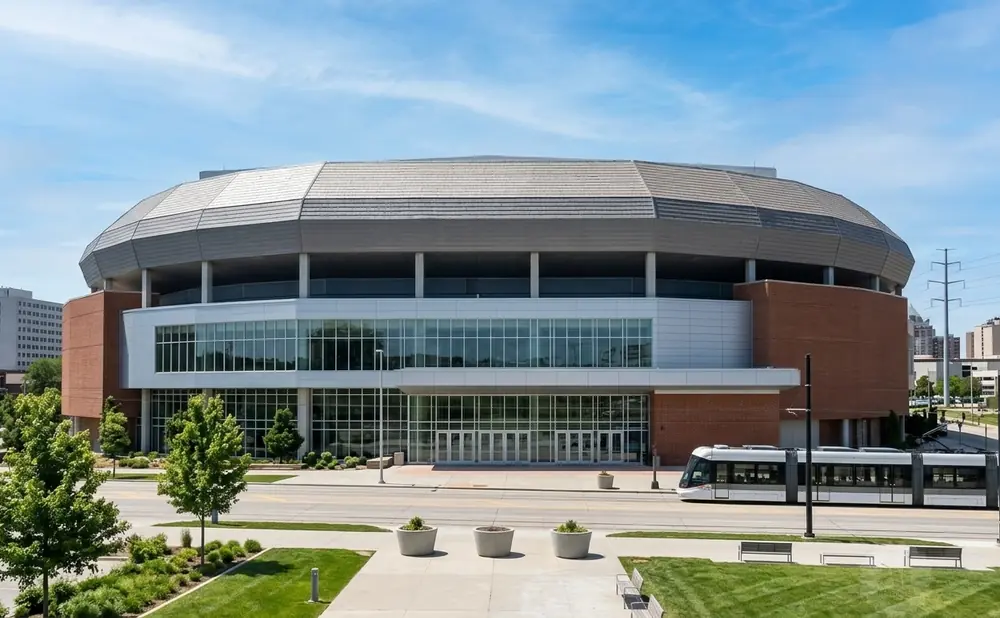 Modern stadium with a large glass facade and a streetcar passing by.