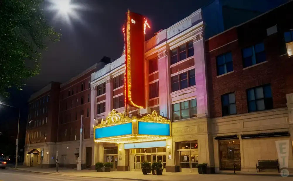 A theater at night, with a large red marquee adorned with lights.