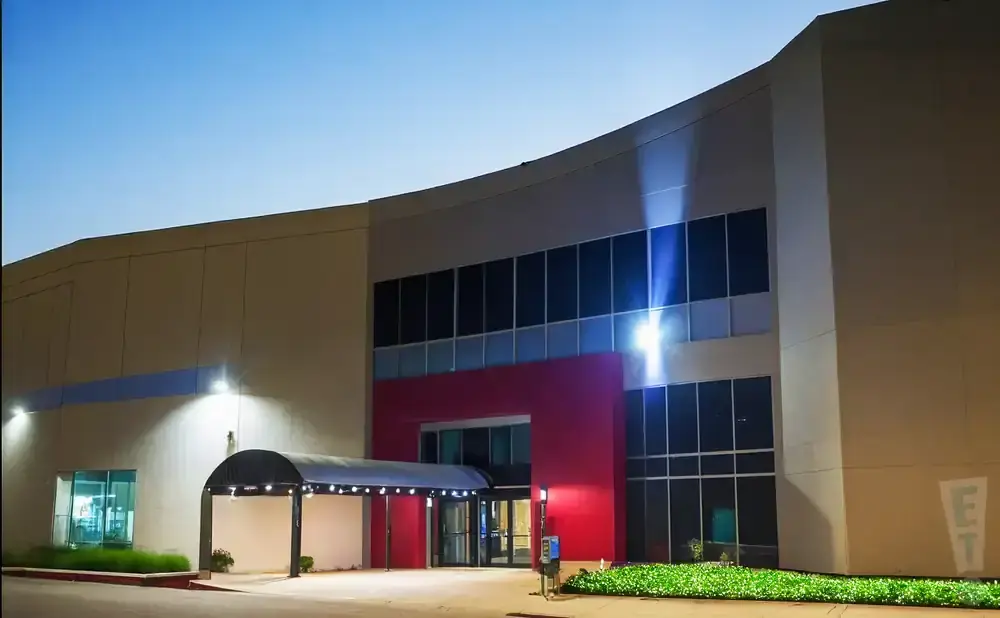 Modern building exterior at dusk with illuminated entrance and bright exterior lighting.