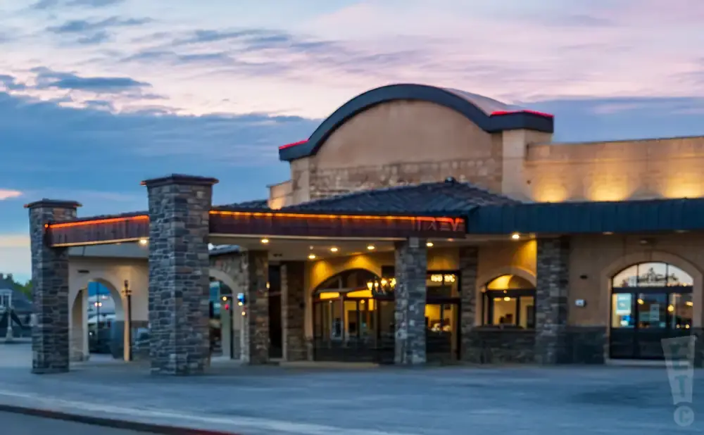 A stone-accented building with warm lighting and a curved roof at dusk.