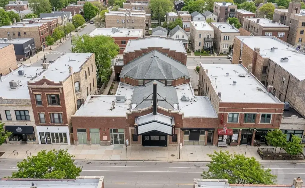 Aerial view of a street with multi-story buildings, featuring brick facades, shops, and a distinctive octagonal-roofed building.