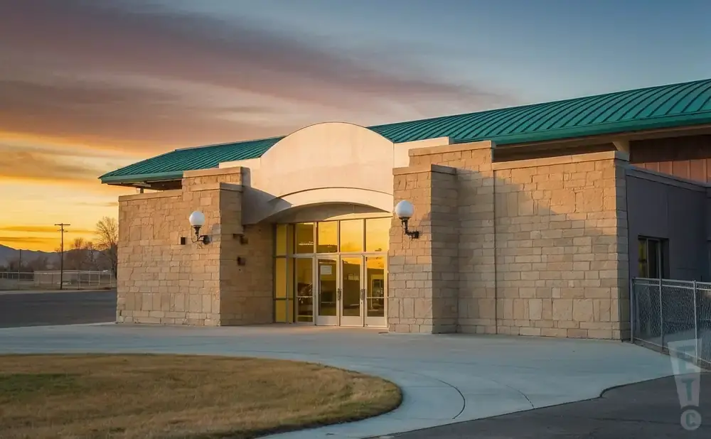Modern building with stone facade and green roof at sunset.