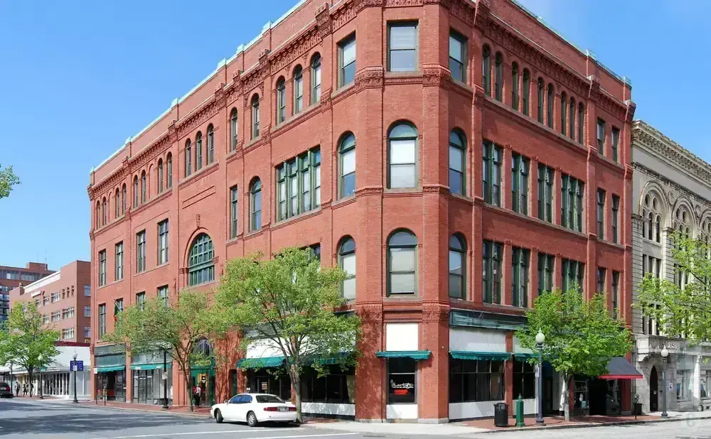 Red brick building with green-trimmed windows on a sunny day.
