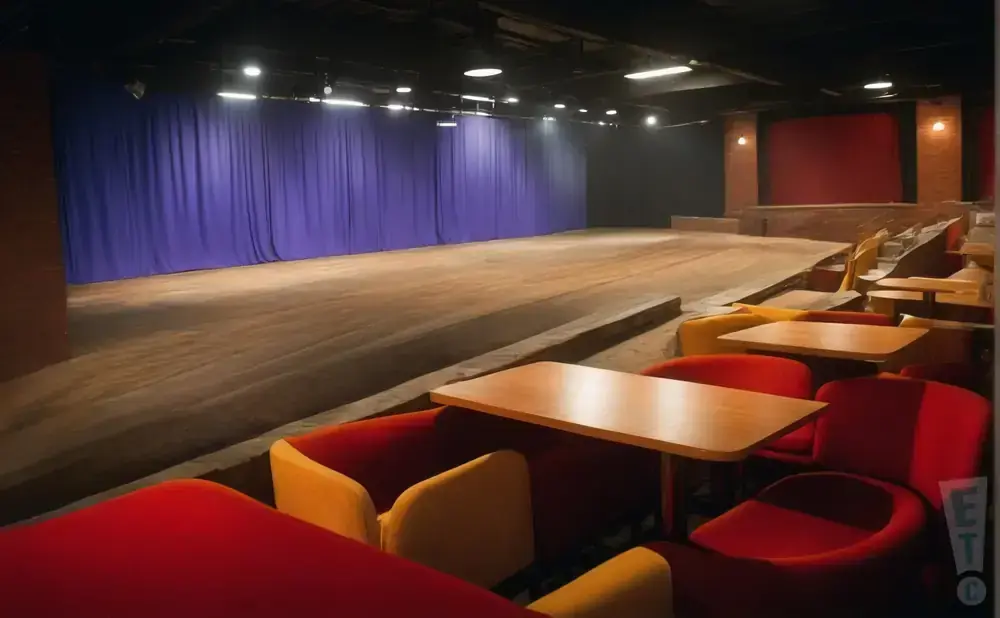 A stage with blue curtains and tiered seating in a theater.