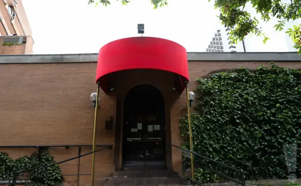 Red awning over a brick building entrance with ivy-covered walls.