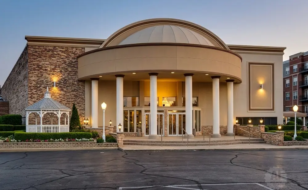 Exterior of a domed building with brick accents, columns, and a white gazebo.