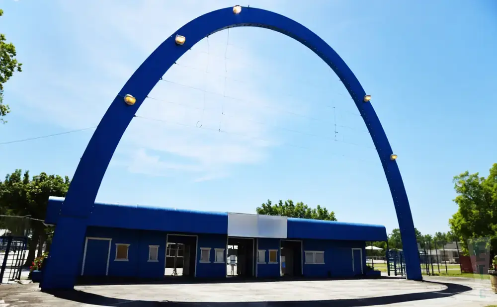 A blue archway over a blue building with white accents under a clear blue sky.