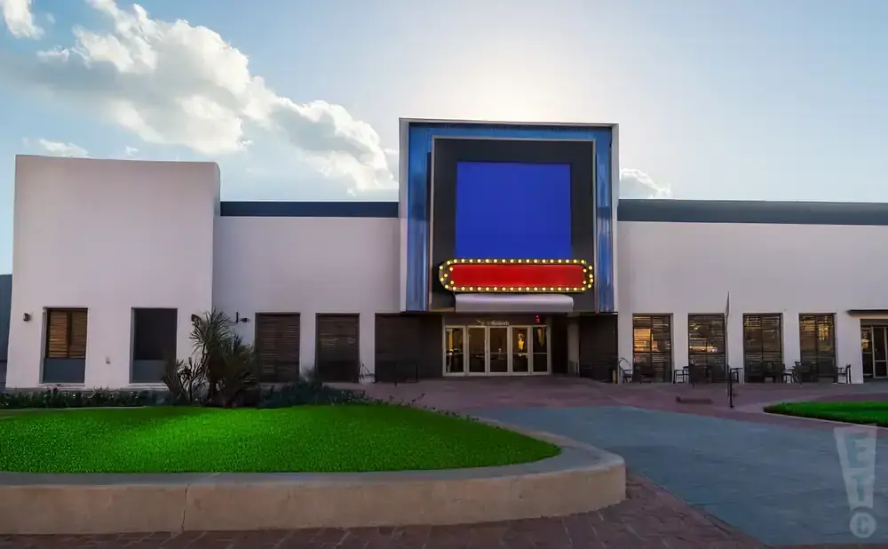 A modern white building with a large blue screen and a vintage marquee entrance.
