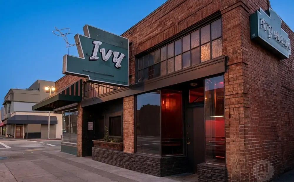 Exterior view of The Ivy Room, a brick building with a prominent green sign featuring the word 