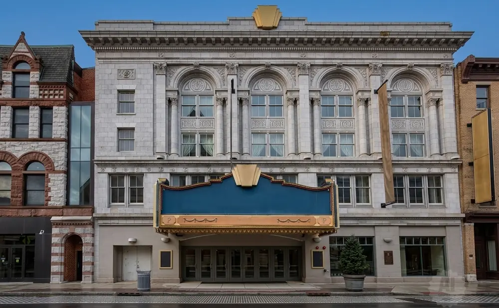 Ornate theater marquee with a blue sign and gold trim in front of a historic building.