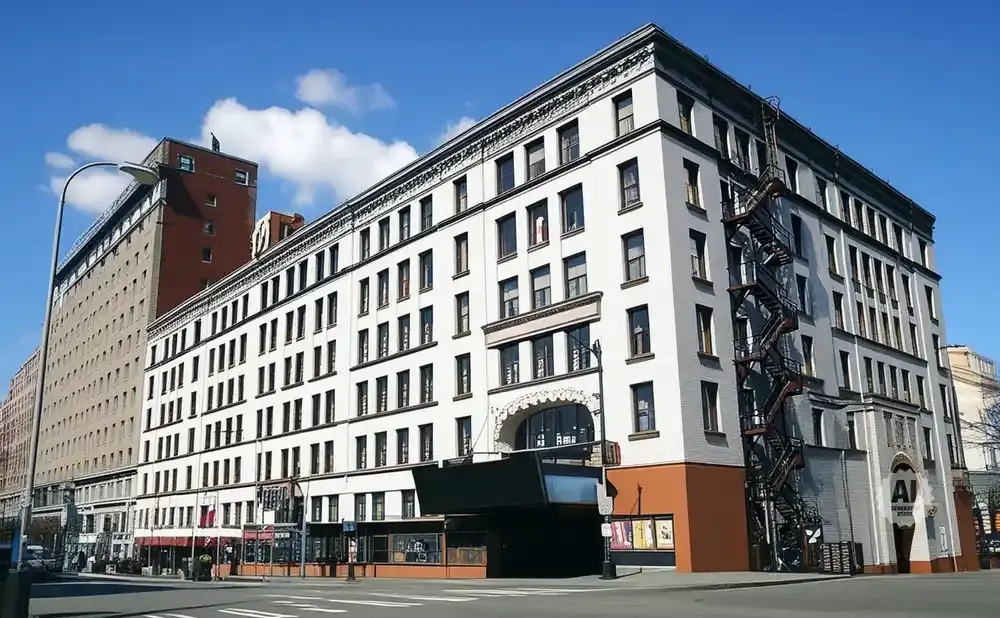 A white, multi-story building with many windows and a fire escape.